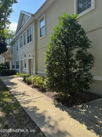 a view of a white house with a yard and potted plants