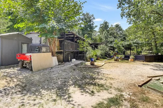 a view of a backyard with large tree and wooden fence