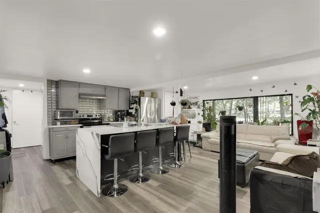 a kitchen with stainless steel appliances a dining table chairs stove refrigerator and cabinets