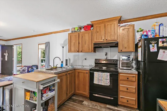 a kitchen with stainless steel appliances granite countertop a stove a sink dishwasher and cabinets with wooden floor