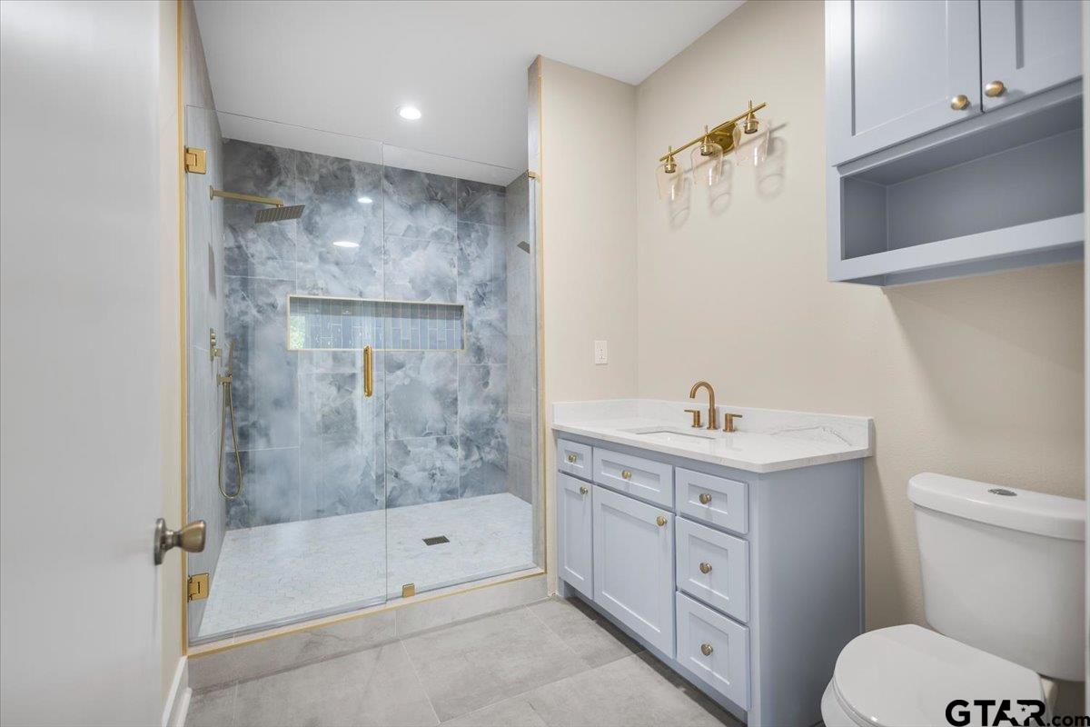 4123 County Road 1120 Tyler, TX 75704 - Photo 25 of 43 a bathroom with a granite countertop sink a toilet and shower