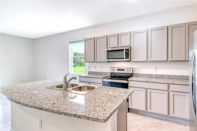 a kitchen with granite countertop a sink a stove and microwave