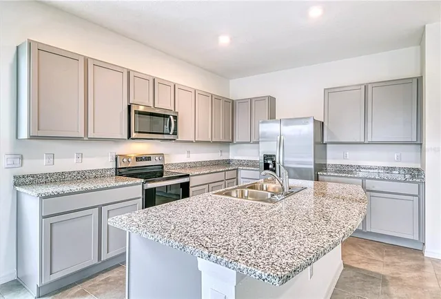 a kitchen with granite countertop a sink stove and refrigerator