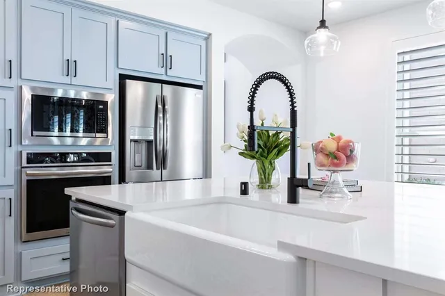 a kitchen with stainless steel appliances granite countertop a refrigerator a stove and a sink with wooden floor