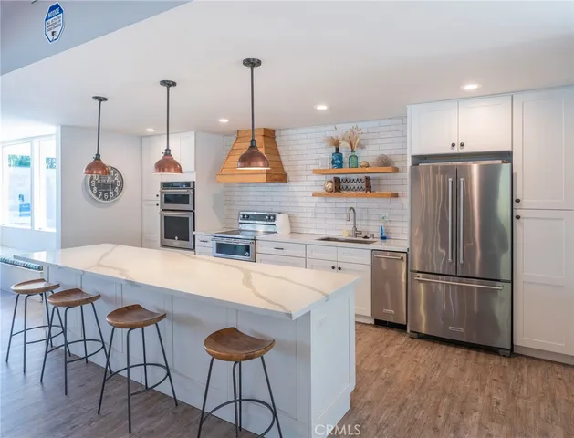 a kitchen with stainless steel appliances granite countertop a refrigerator a sink dishwasher a stove and a refrigerator with wooden floor