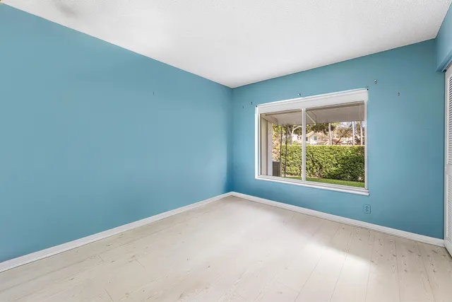 an empty room with wooden floor ceiling fan and window