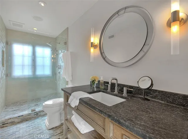 a bathroom with a sink a toilet a large mirror and shower