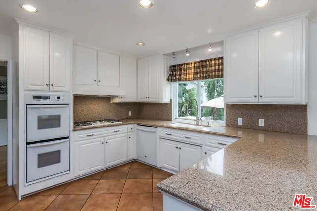a kitchen with stainless steel appliances granite countertop a stove a sink and white cabinets