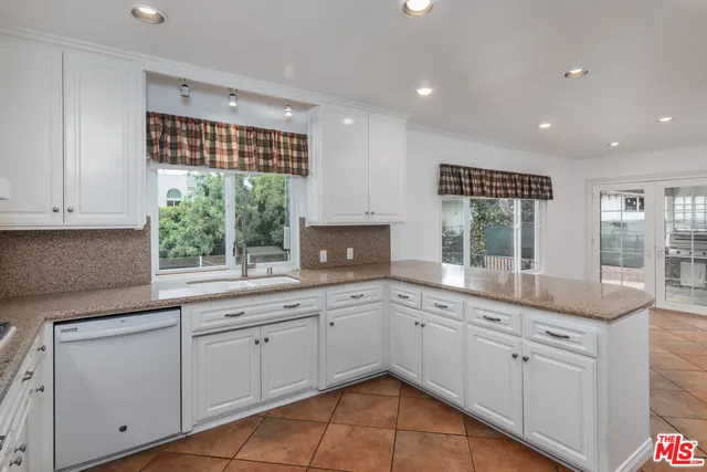 a kitchen with granite countertop white cabinets and a window