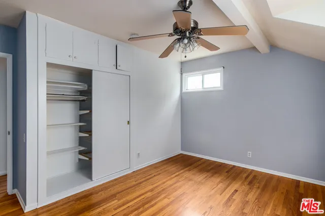 a view of empty room with wooden floor and fan