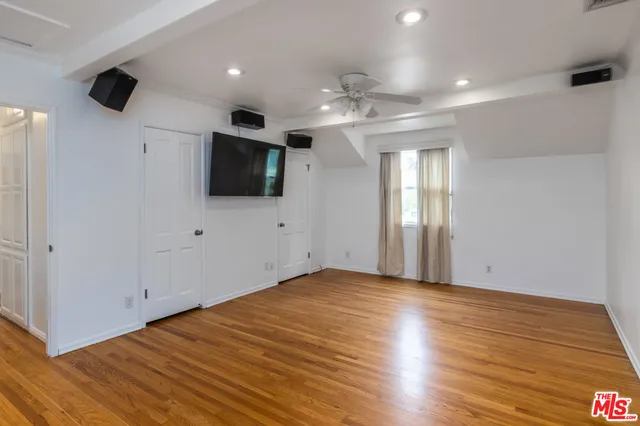 a view of a livingroom with wooden floor and a ceiling fan