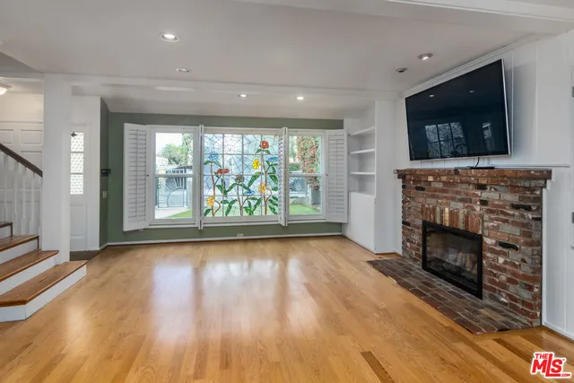 an empty room with wooden floor fireplace and windows