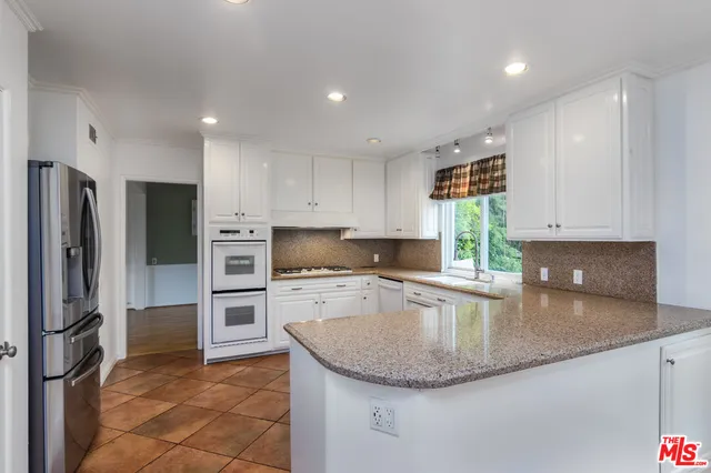 a kitchen with stainless steel appliances granite countertop a sink a stove a refrigerator a washer and dryer