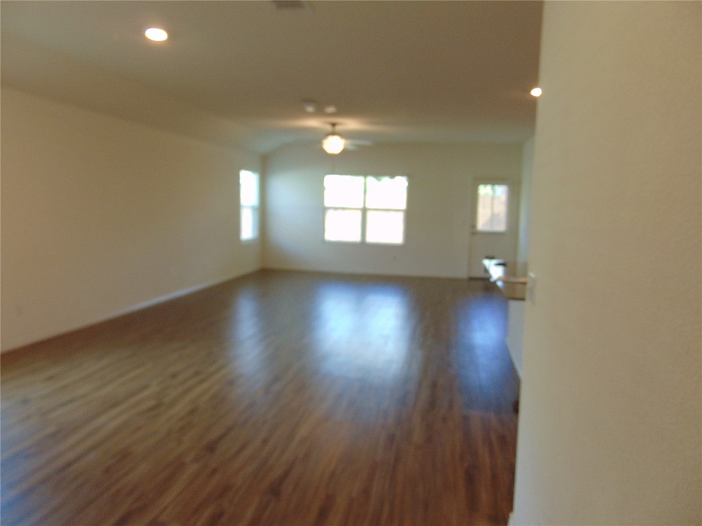 181 Crystal River Road Kyle, TX 78640 - Photo 5 of 12 an empty room with wooden floor and windows