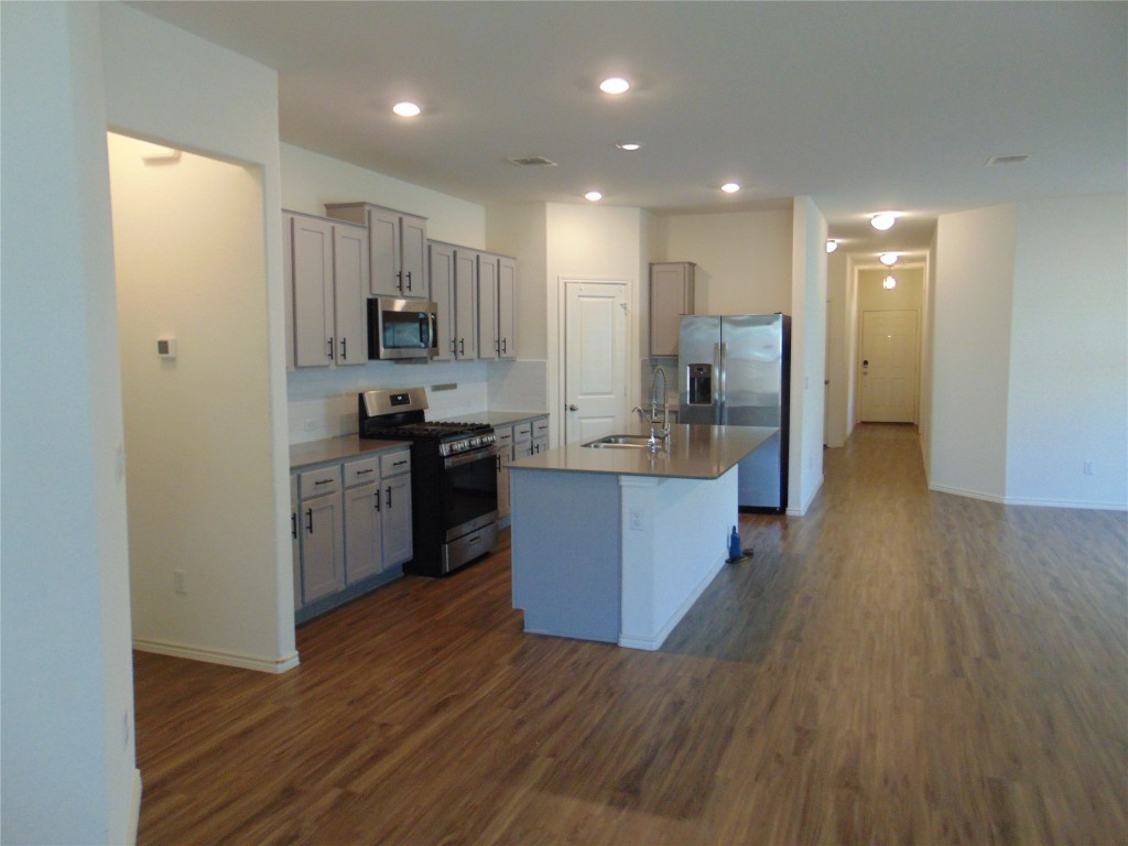 181 Crystal River Road Kyle, TX 78640 - Photo 7 of 12 a large kitchen with stainless steel appliances kitchen island a large counter top and a wooden floors