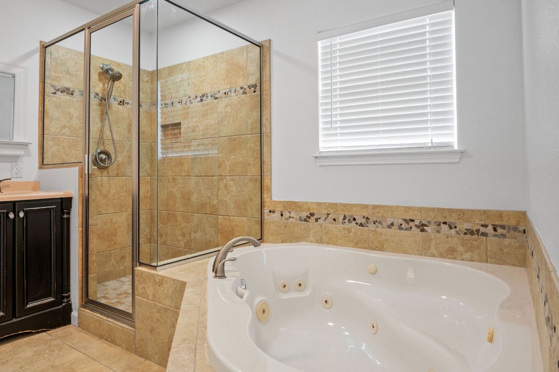 7517 Delafield Lane Austin, TX 78752 - Photo 21 of 39 Full bathroom featuring a whirlpool tub, a shower stall, vanity, and light tile patterned floors