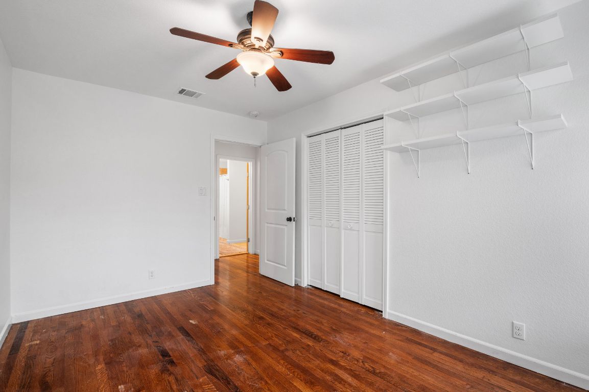 7517 Delafield Lane Austin, TX 78752 - Photo 22 of 39 Unfurnished bedroom featuring dark wood-type flooring, a ceiling fan, and a closet