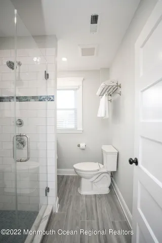 a view of a hallway with wooden floor and a bathroom