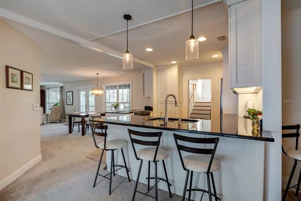 a dining hall with stainless steel appliances kitchen island a table and chairs