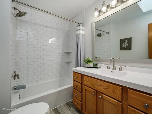 a bathroom with a bathtub shower sink vanity mirror and toilet