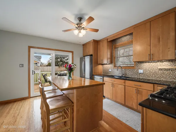 a kitchen with stainless steel appliances granite countertop a stove top oven a sink a dining table and chairs with wooden floor