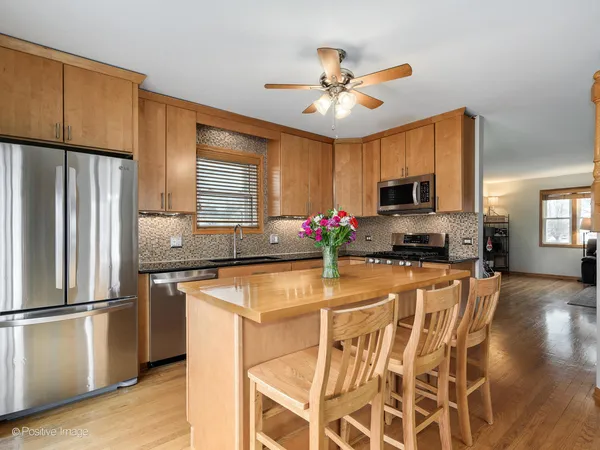 a kitchen with stainless steel appliances kitchen island granite countertop a refrigerator a stove top oven a sink dishwasher and a refrigerator