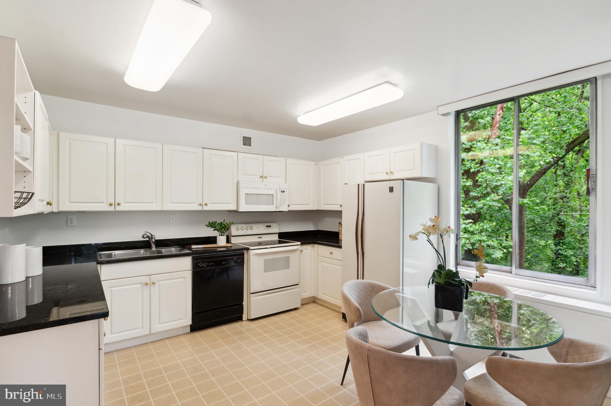 4100 Cathedral Avenue Northwest, Unit 709 Washington, DC 20016 - Photo 5 of 20 a kitchen with stainless steel appliances granite countertop white cabinets a stove a refrigerator with a dining table and chairs