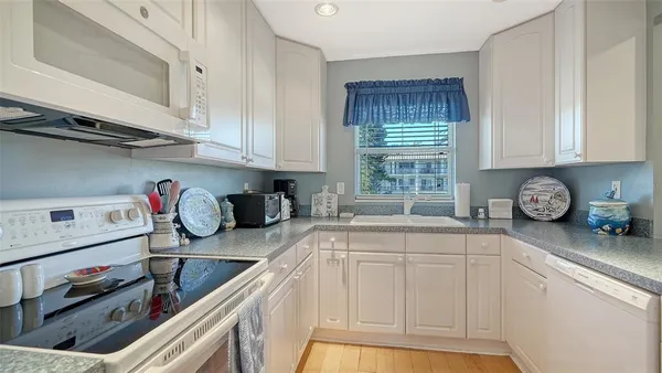 a kitchen with granite countertop a sink a stove and cabinets