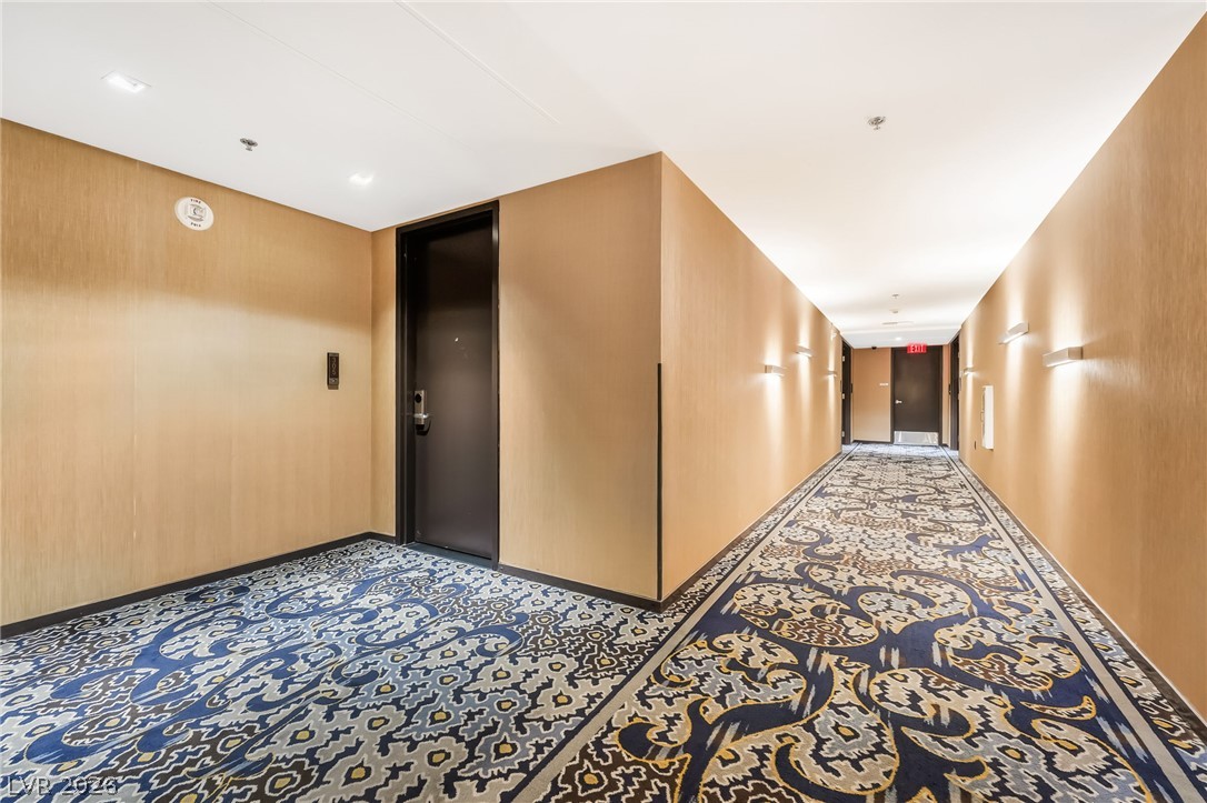 4381 West Flamingo Road, Unit 18305 Las Vegas, NV 89103 - Photo 18 of 19 A well-lit corridor with an intricate patterned carpet leads to private residences.