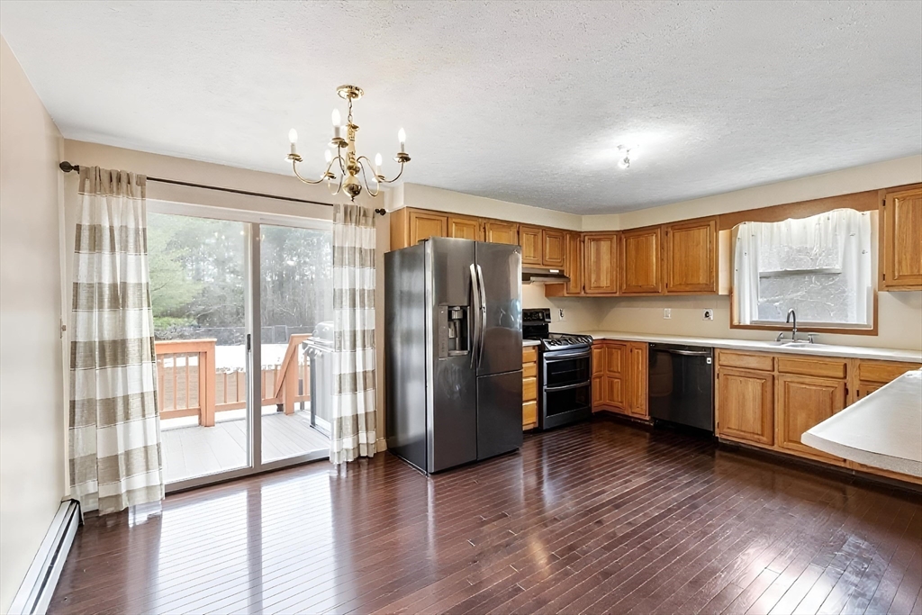 681 Teel Road Winchendon, MA 01475 - Photo 5 of 27 a kitchen with granite countertop a refrigerator a sink dishwasher a stove and white cabinets with wooden floor