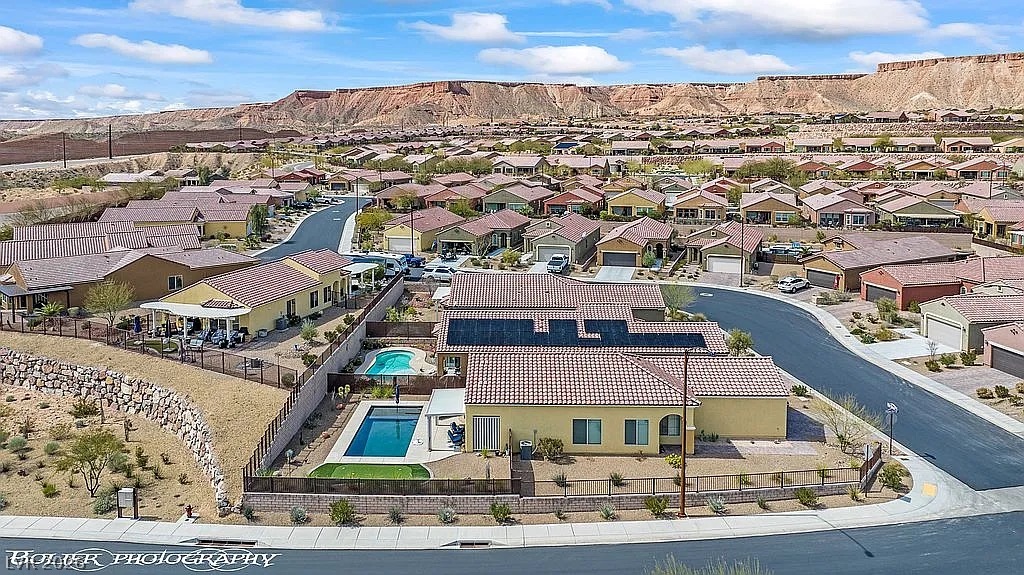 1304 Cottage Ridge Mesquite, NV 89034 - Photo 45 of 52 An aerial perspective reveals a vibrant neighborhood nestled against rugged hillsides, featuring residential properties with private pools.