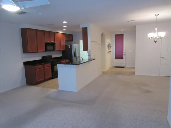 a kitchen with stainless steel appliances kitchen island granite countertop a refrigerator a stove a microwave oven a sink with island and chairs