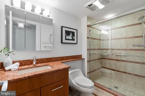 a bathroom with a granite countertop sink toilet and shower