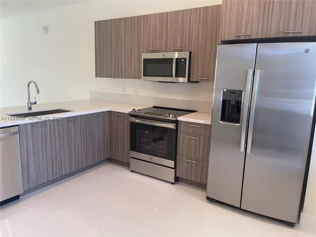 a kitchen with stainless steel appliances granite countertop a refrigerator a stove a sink and a oven