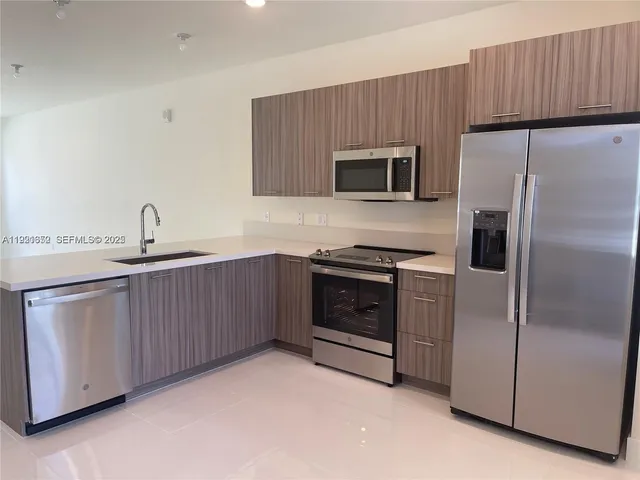 a kitchen with stainless steel appliances a refrigerator sink and microwave