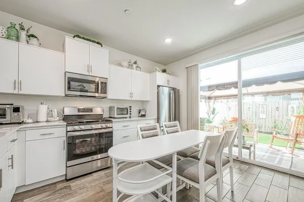 a kitchen with stainless steel appliances a stove a sink dishwasher a refrigerator with white cabinets and wooden floor