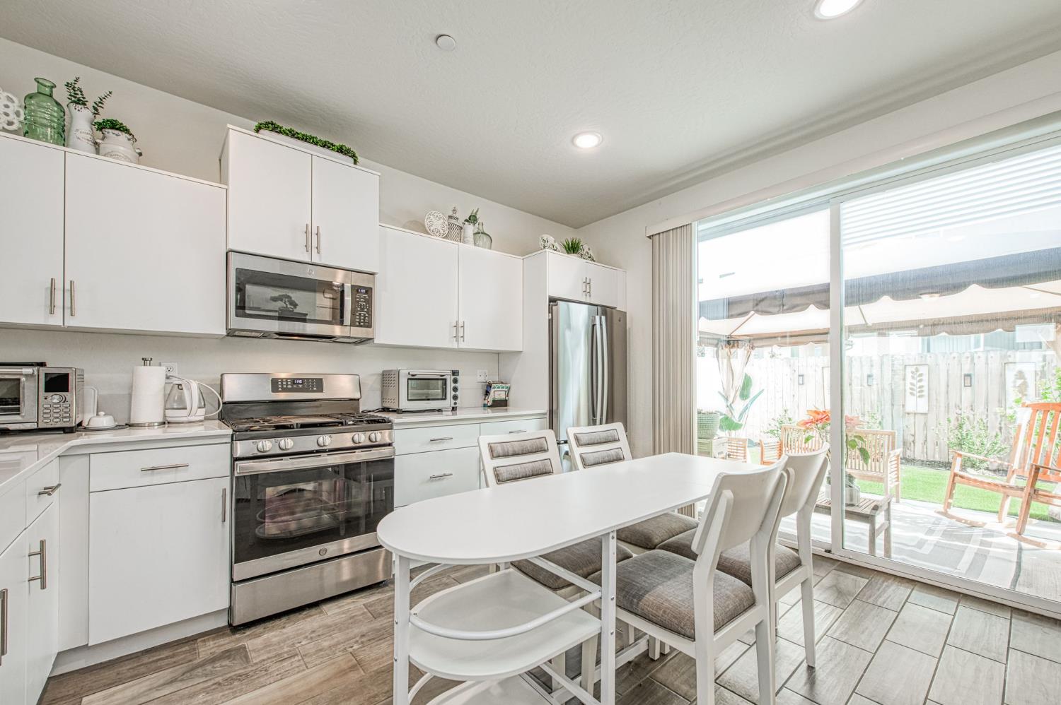 2053 North Ralph Lane Clovis, CA 93619 - Photo 11 of 31 a kitchen with stainless steel appliances a stove a sink dishwasher a refrigerator with white cabinets and wooden floor