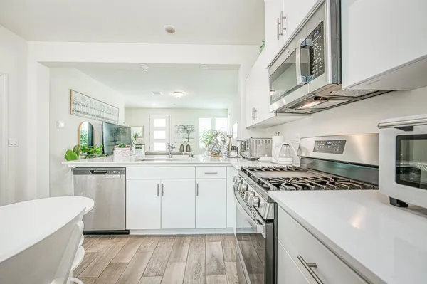 a kitchen with stainless steel appliances a white stove top oven and white cabinets