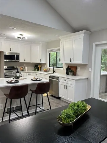 a kitchen with stainless steel appliances kitchen island granite countertop a sink a stove a refrigerator and a microwave