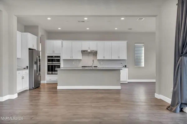 a large kitchen with stainless steel appliances granite countertop a lot of counter space and wooden floors