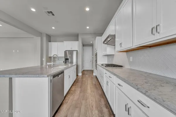 a large kitchen with stainless steel appliances lots of counter space and wooden floor