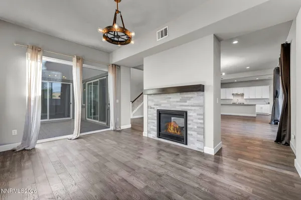 a view of an empty room with wooden floor and a kitchen