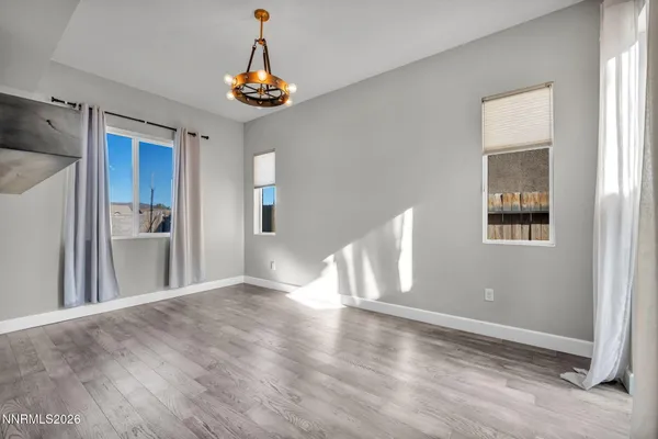 an empty room with wooden floor fireplace and chandelier