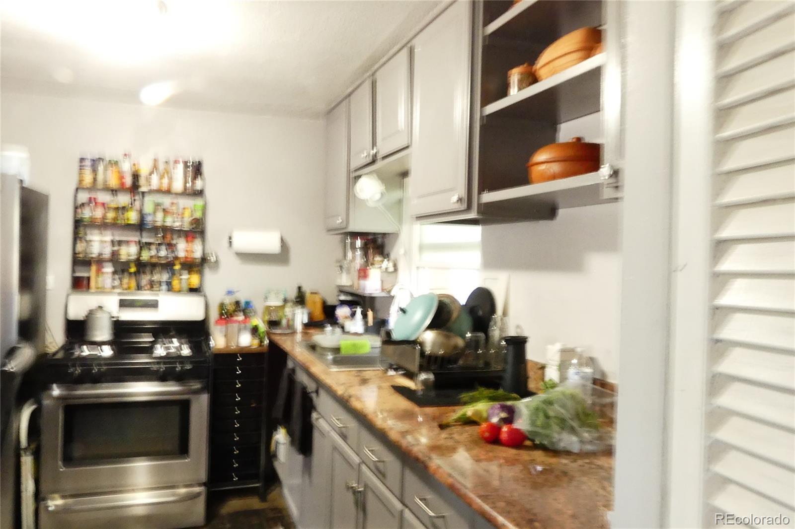 4851 Adams Street Denver, CO 80216 - Photo 24 of 30 a kitchen with stainless steel appliances a sink and a stove