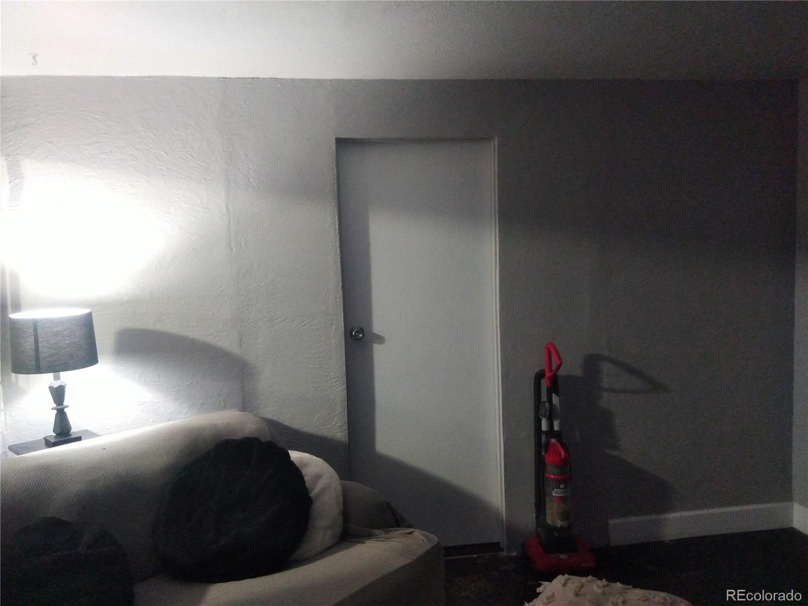 4851 Adams Street Denver, CO 80216 - Photo 28 of 30 a bed sitting in a bedroom next to a lamp