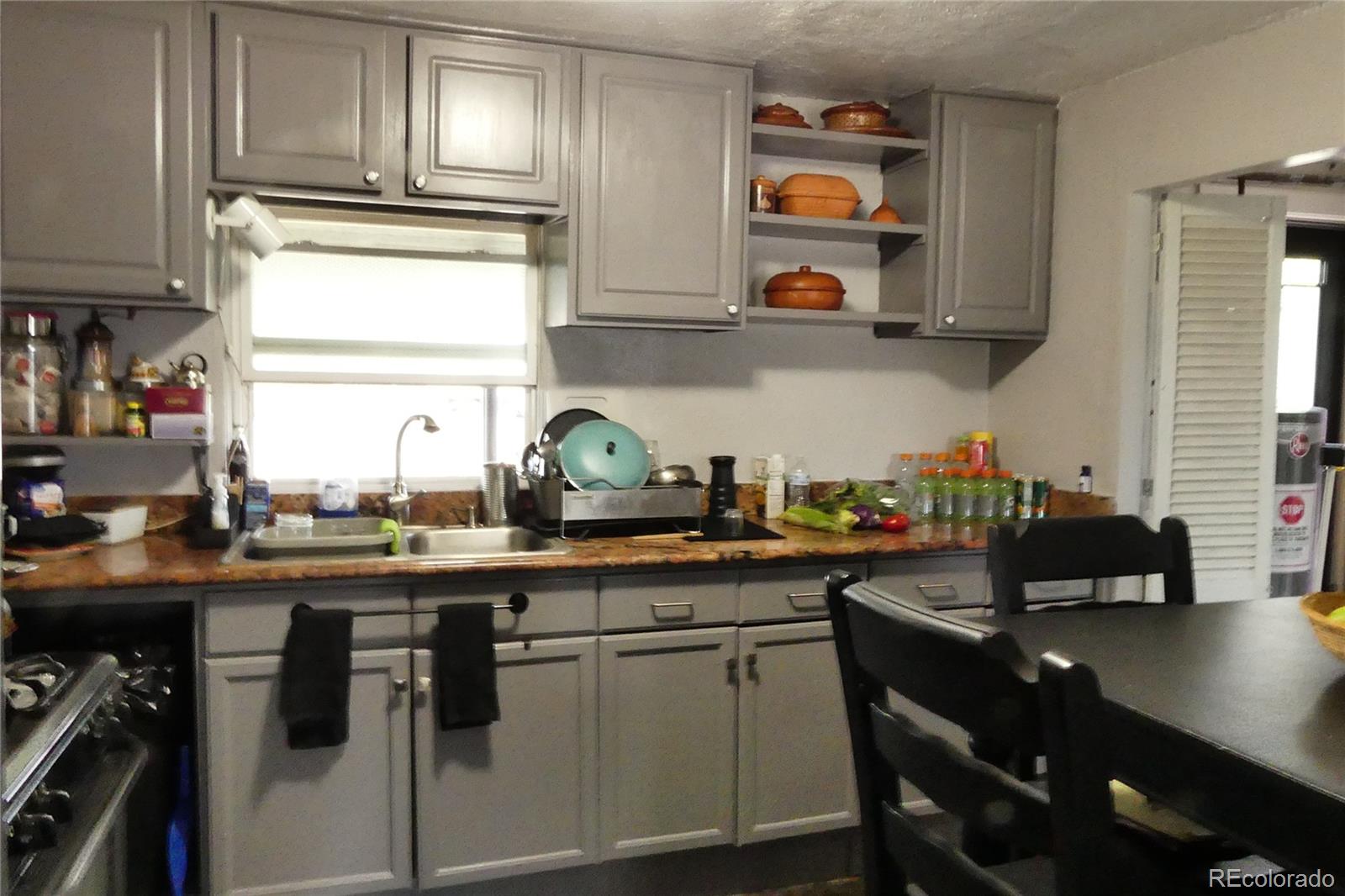 4851 Adams Street Denver, CO 80216 - Photo 6 of 30 a kitchen with stainless steel appliances a sink a stove and cabinets