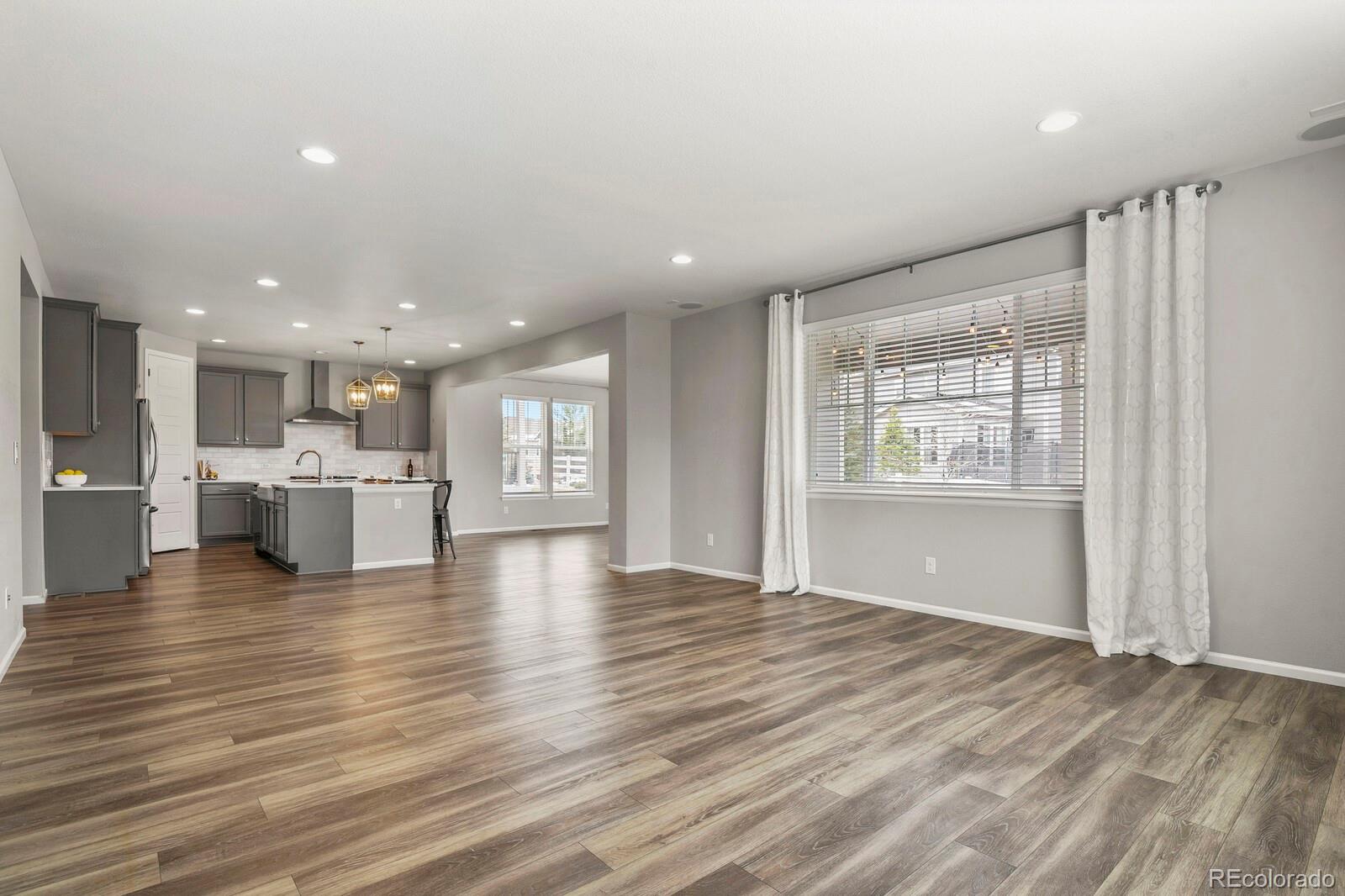 5723 Berry Ridge Wy. Castle Rock, CO 80104 - Photo 15 of 48 a view of an empty room with wooden floor and a kitchen
