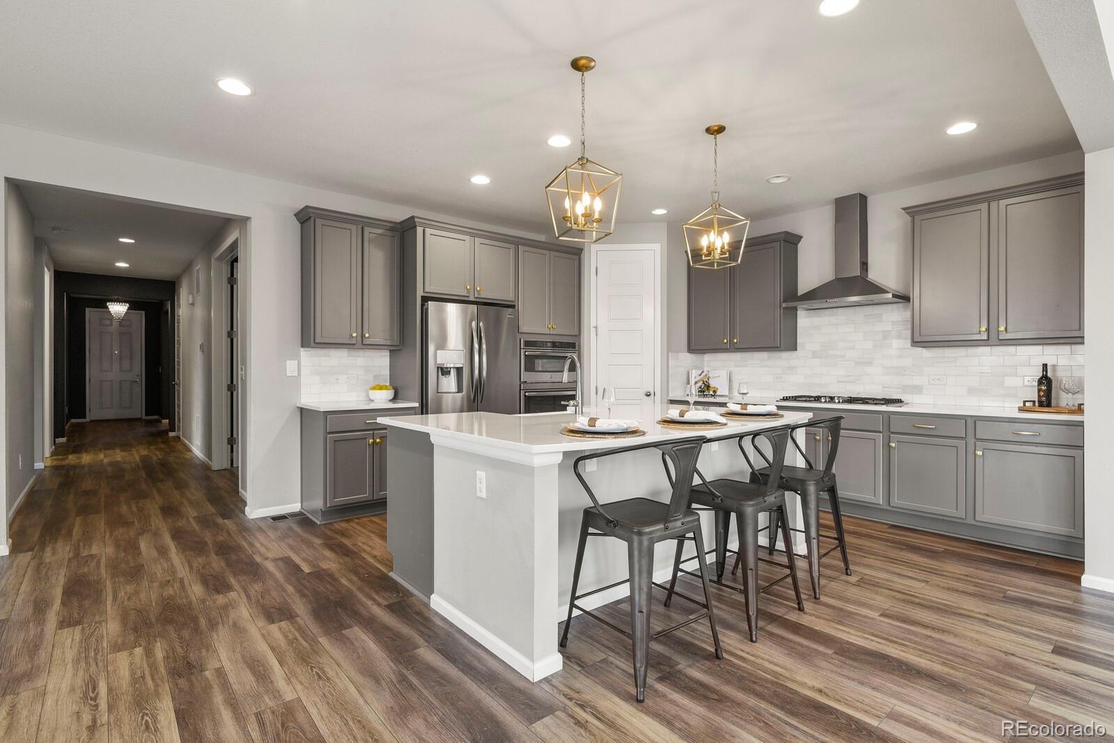 5723 Berry Ridge Wy. Castle Rock, CO 80104 - Photo 6 of 48 a kitchen with kitchen island granite countertop a sink cabinets and wooden floor