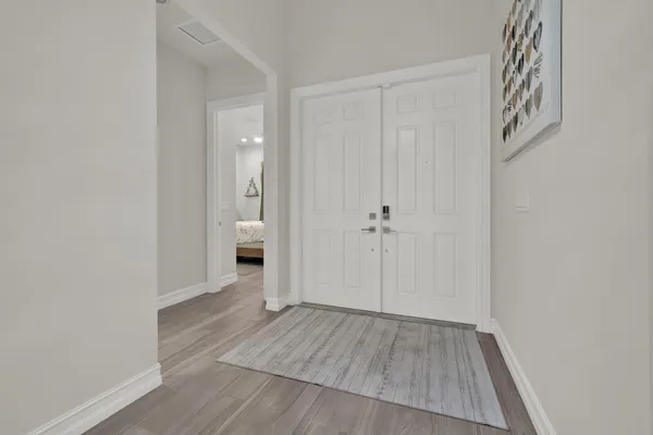 a view of a hallway with wooden floor and a bathroom