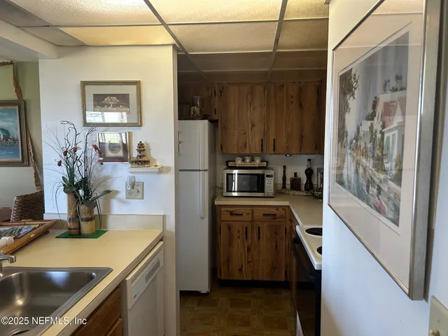 a kitchen with a refrigerator a stove and a sink with wooden floor